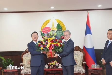 Đại sứ Nguyễn Minh Tâm tặng hoa chúc mừng 49 năm Quốc khánh Lào cho Bộ trưởng Bộ Ngoại giao Lào Thongsavanh Phomvihane. (Ảnh: Xuân Tú/TTXVN)